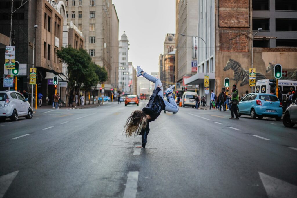 A skilled dancer performs an energetic move in the bustling streets of Johannesburg.