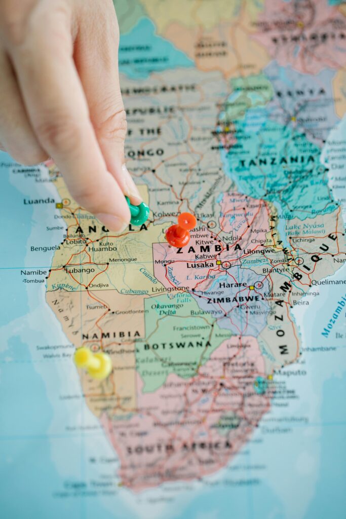 Close-up of a hand placing pushpins on a map of Africa, highlighting various locations.